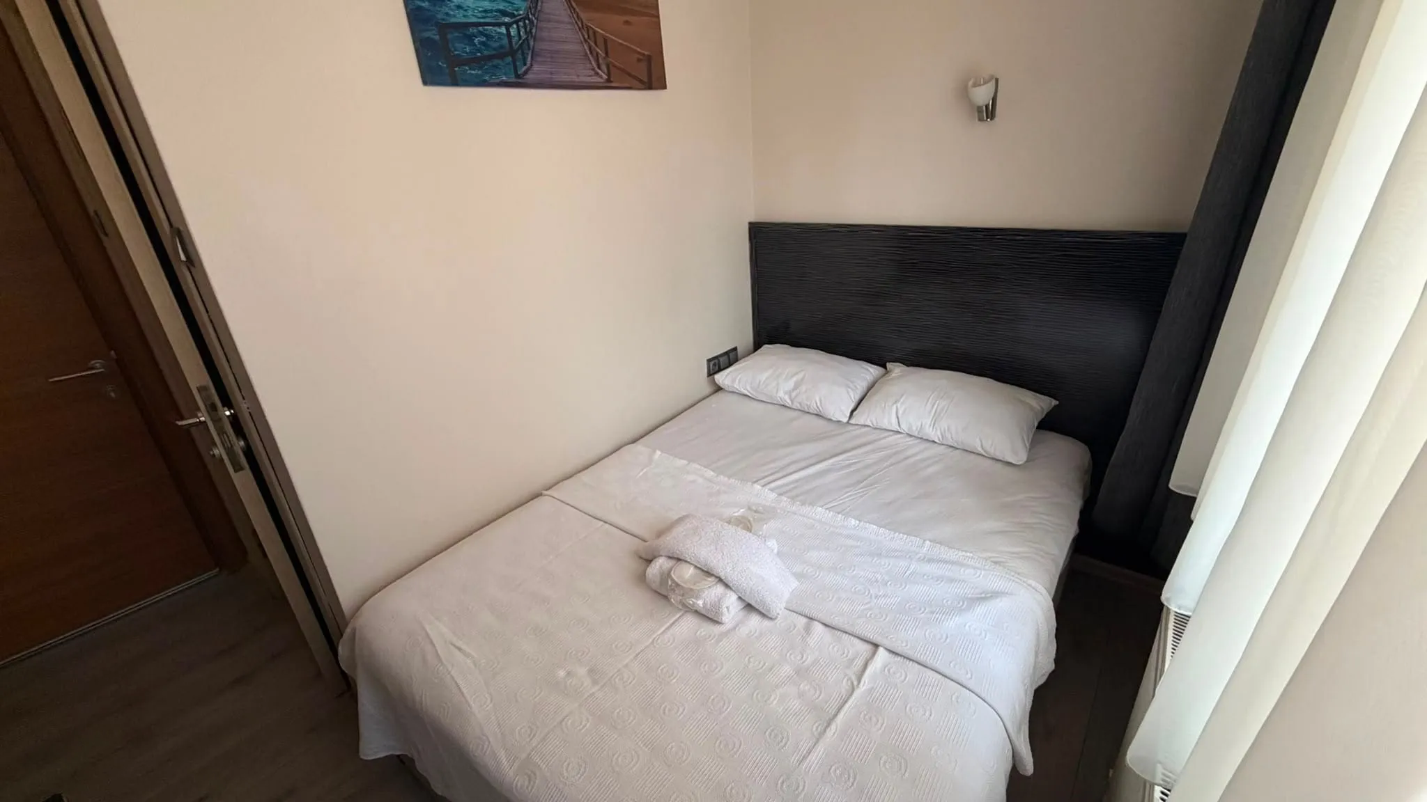 Aile odasında çift kişilik yatak, katlanmış havlular ve oda kapısı
