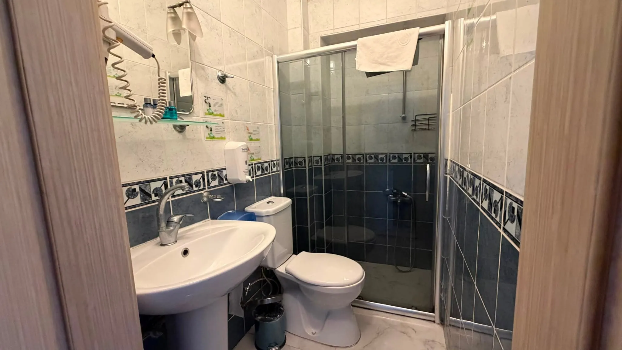 Ekonomik oda banyosu: cam kabinli duş, lavabo ve saç kurutma makinesi