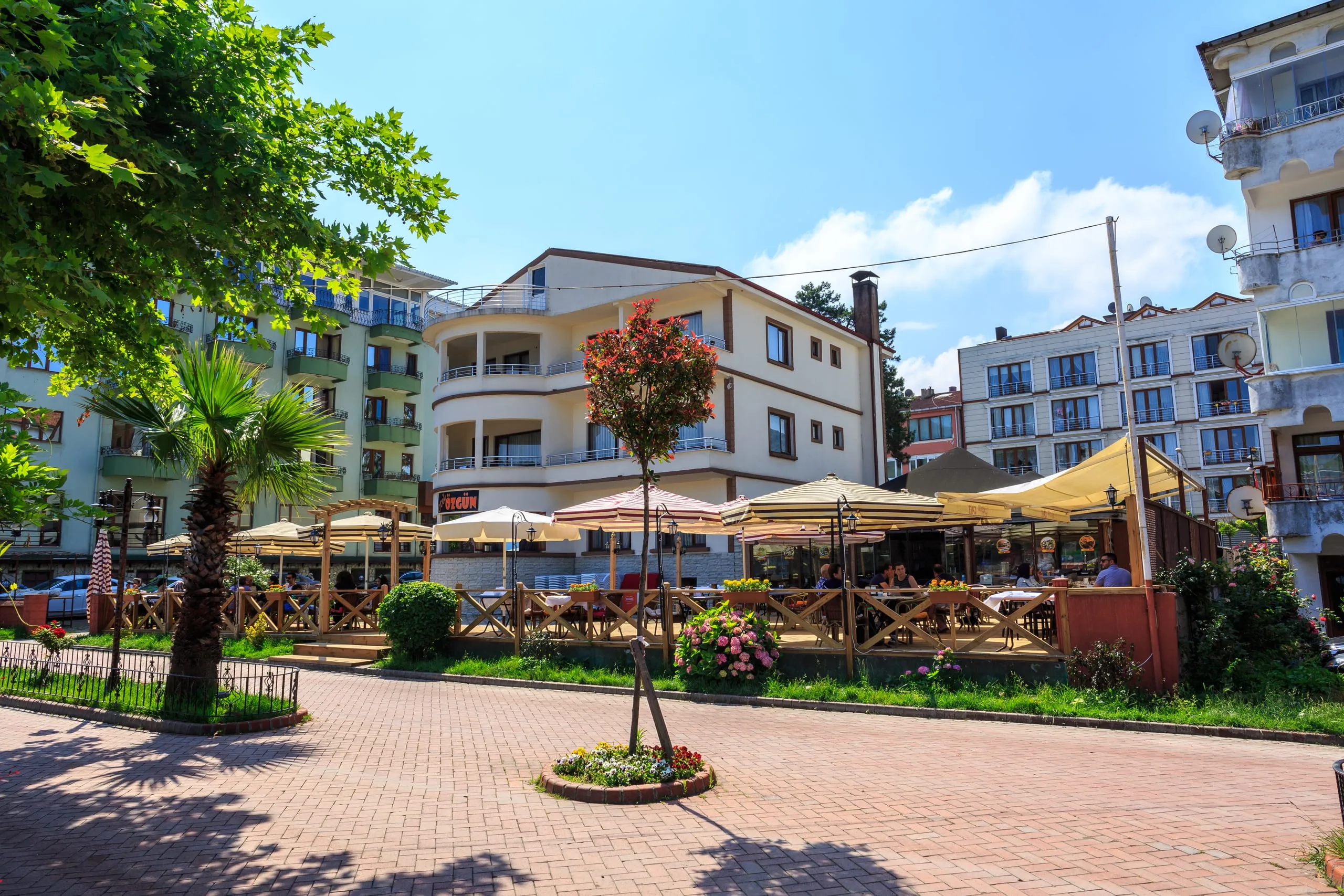 Amasra Özgün Otel gündüz: meydandan bakışta otel binası ve önündeki şemsiyeli Özgün Cafe terası